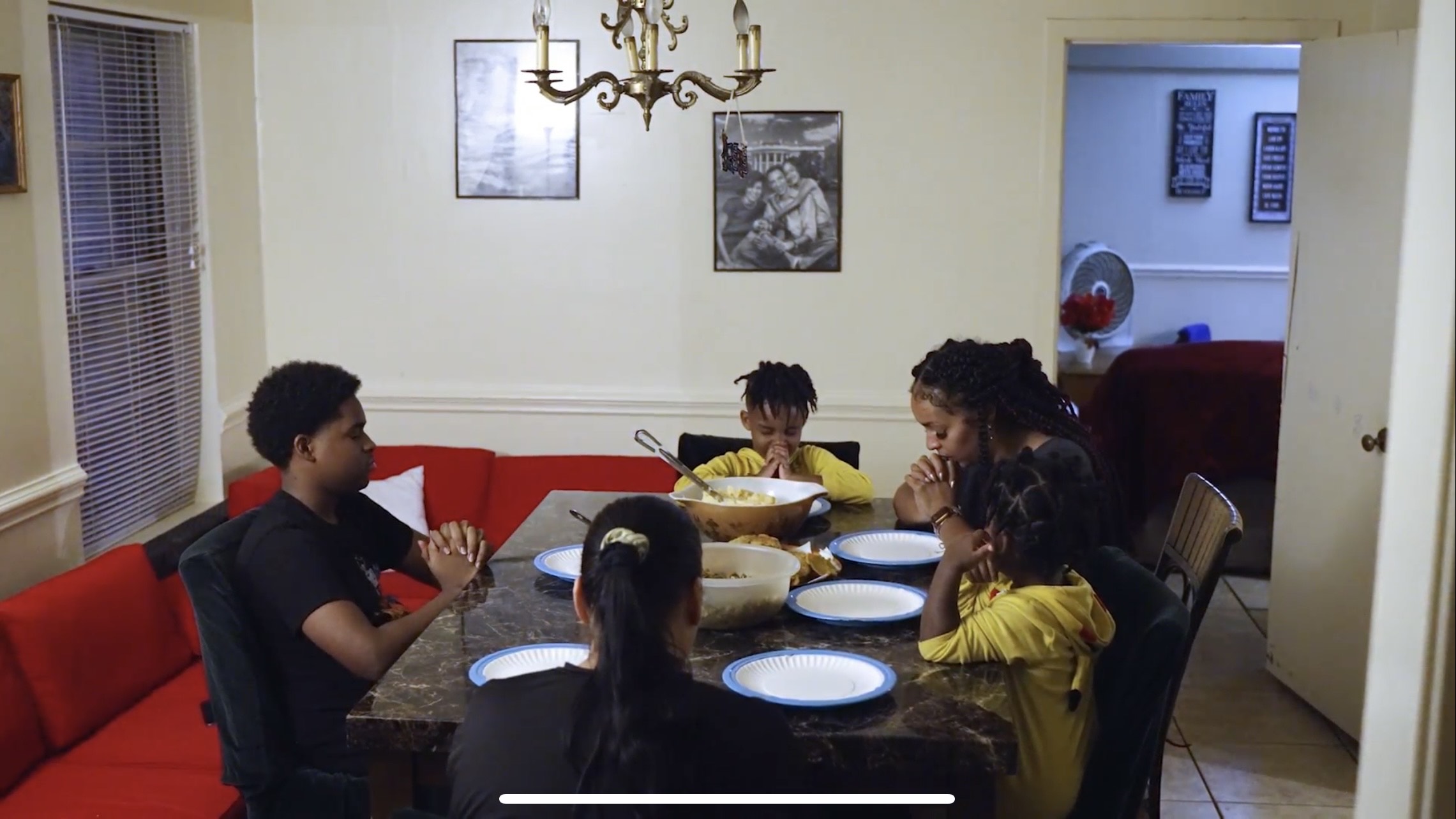 A family of five sits at the dinner and prays together