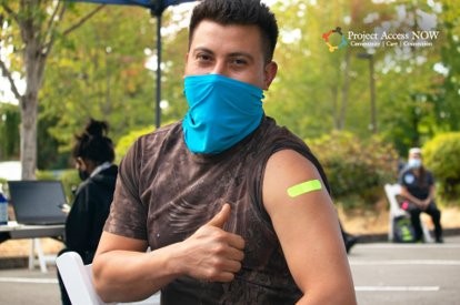 A man gives the thumbs up and shows off the bandaid on his arm where he received his vaccine