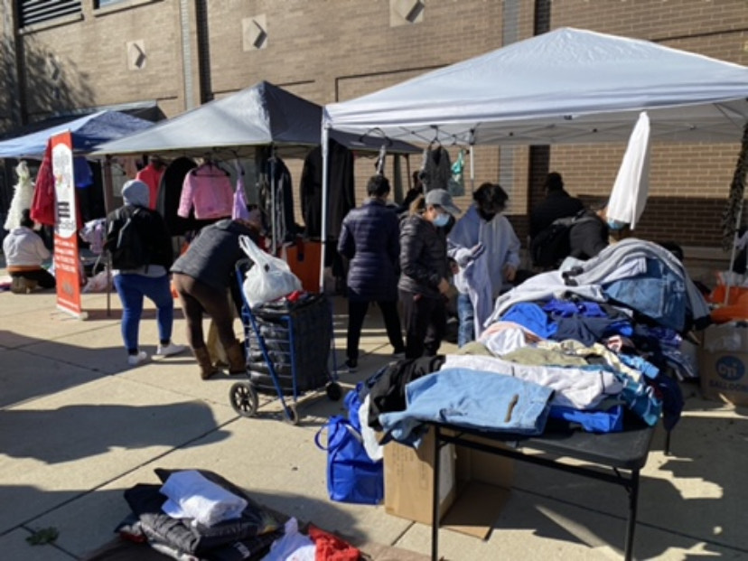 People at a clothing drive look at an assortment of clothes under tents 