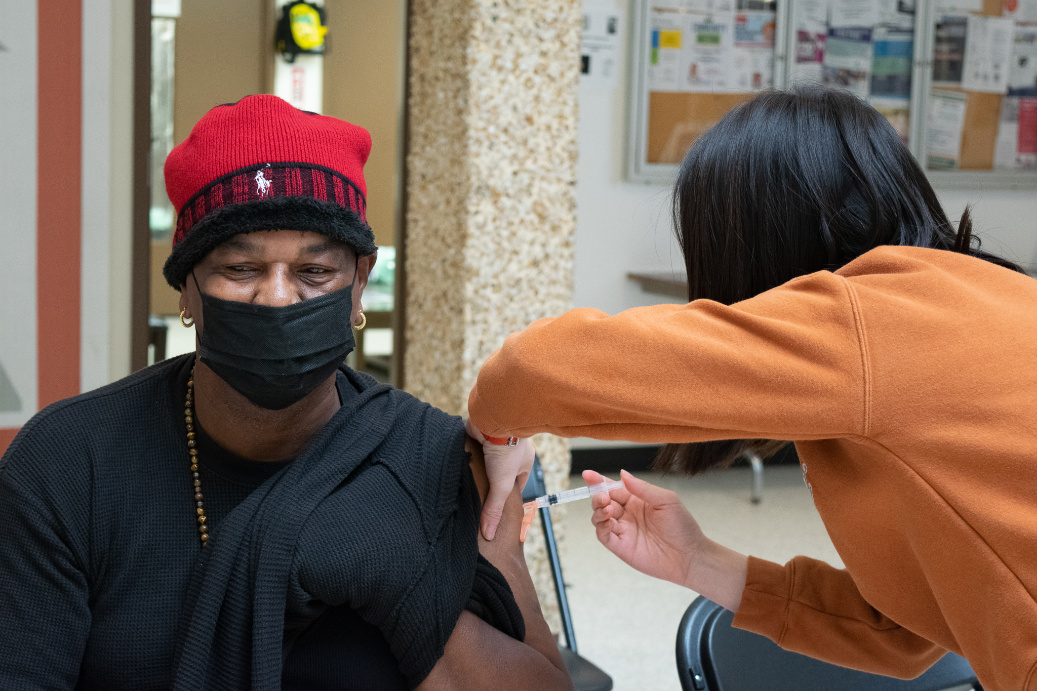 A Black person wearing a mask get a vaccine 