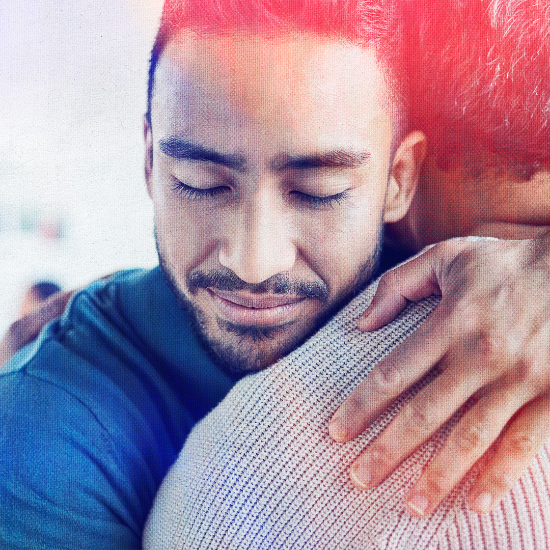 Closeup colorized photograph of a person smiling with eyes closed while hugging a personSample alt text
