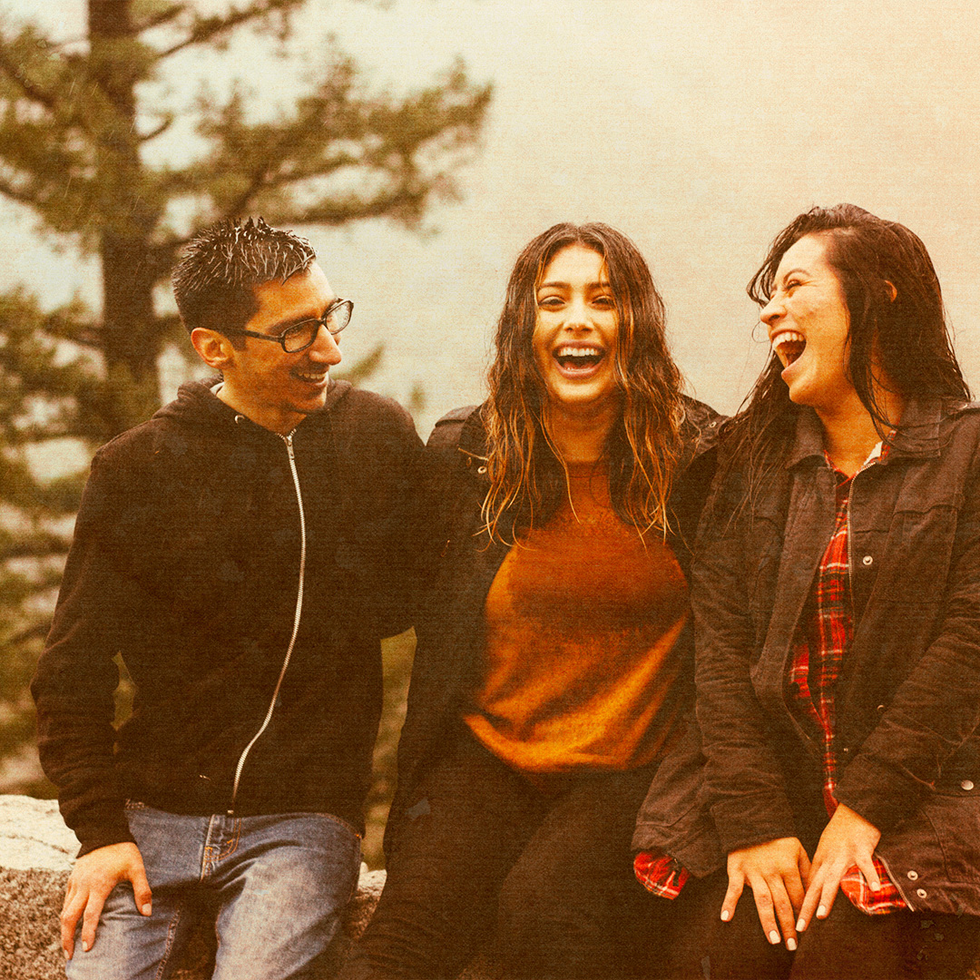 Colorized photograph of three people looking at each other and smiling