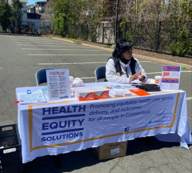 A woman sits at a information table at a community event