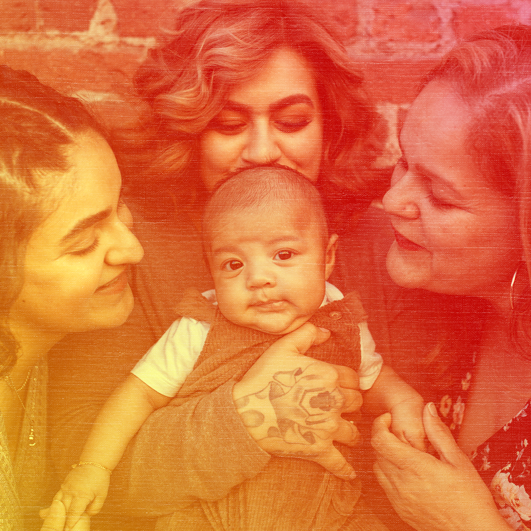 Red colorized photo of three women standing close together and smiling at the baby the center woman is holding.