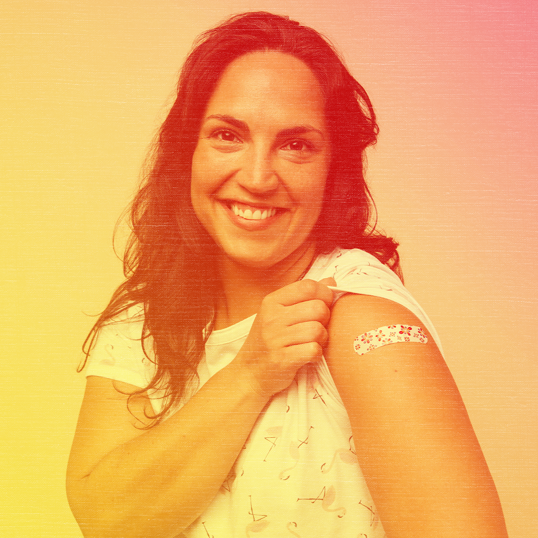 Red colorized photo of a woman smiling and showing off her bandaged arm post-vaccination.