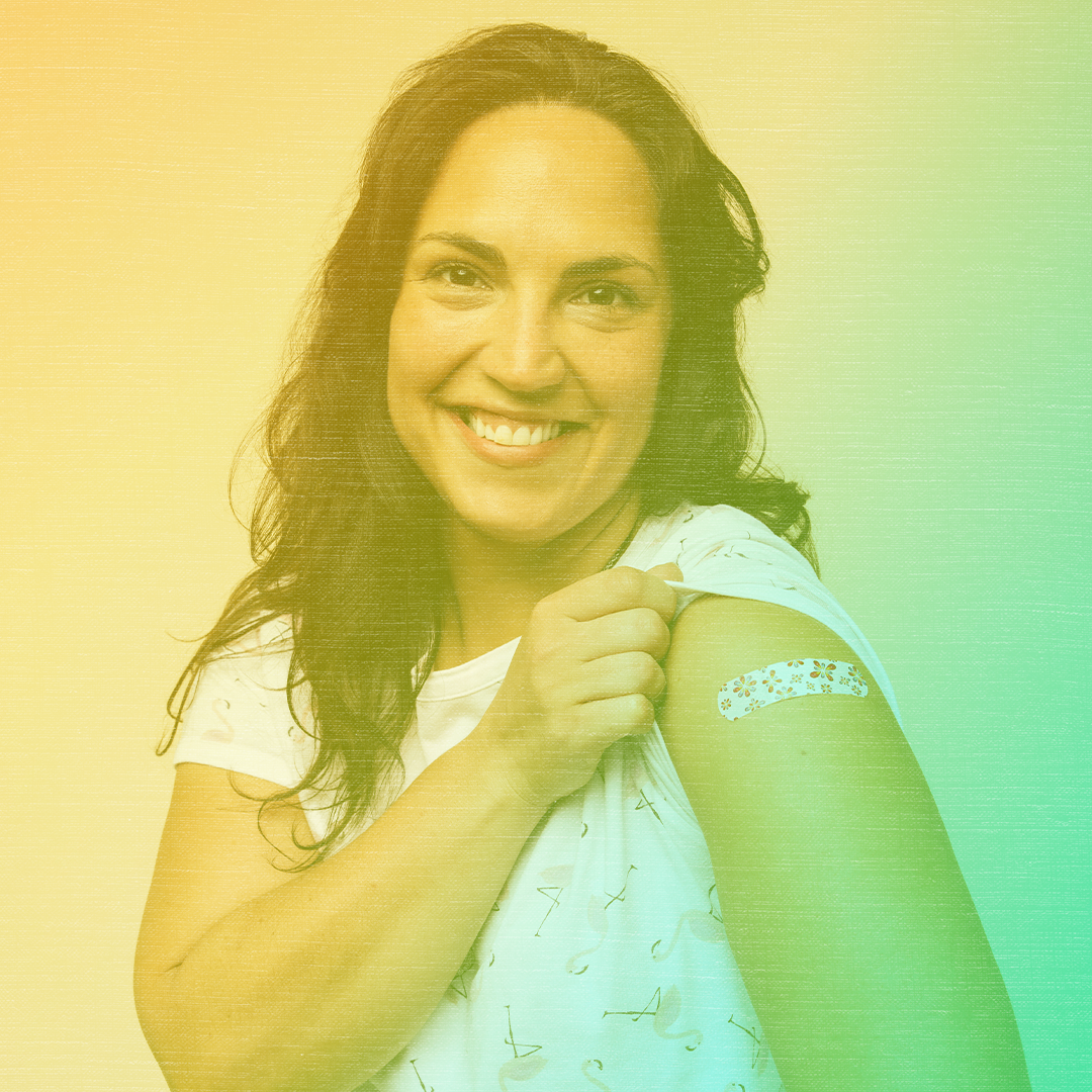 Greenish-yellow colorized photo of a woman smiling and showing off her bandaged arm post-vaccination.
