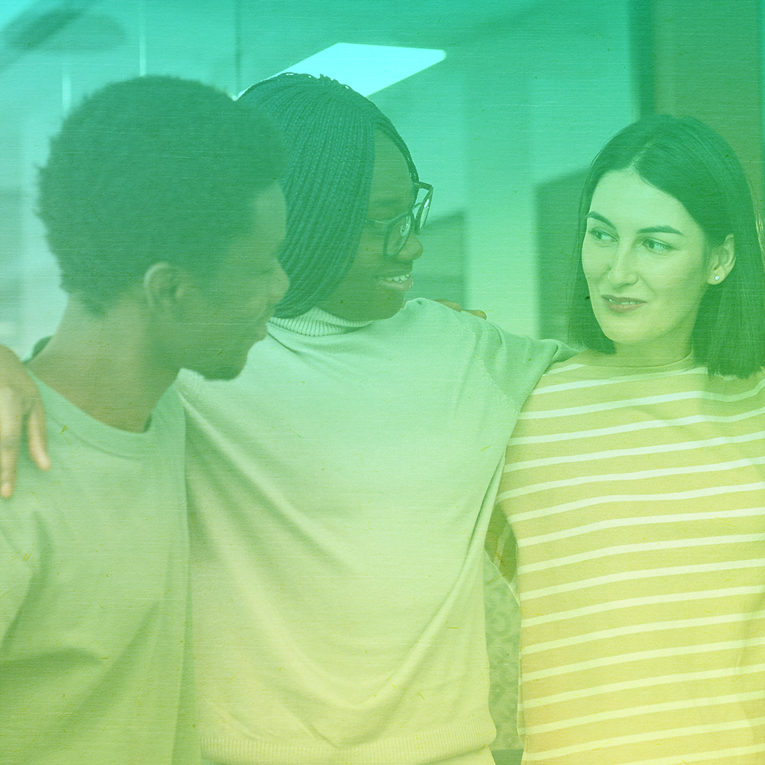 greenish-yellow filtered photo of three young adults, a Black man, Black woman, and White woman with their arms around each other