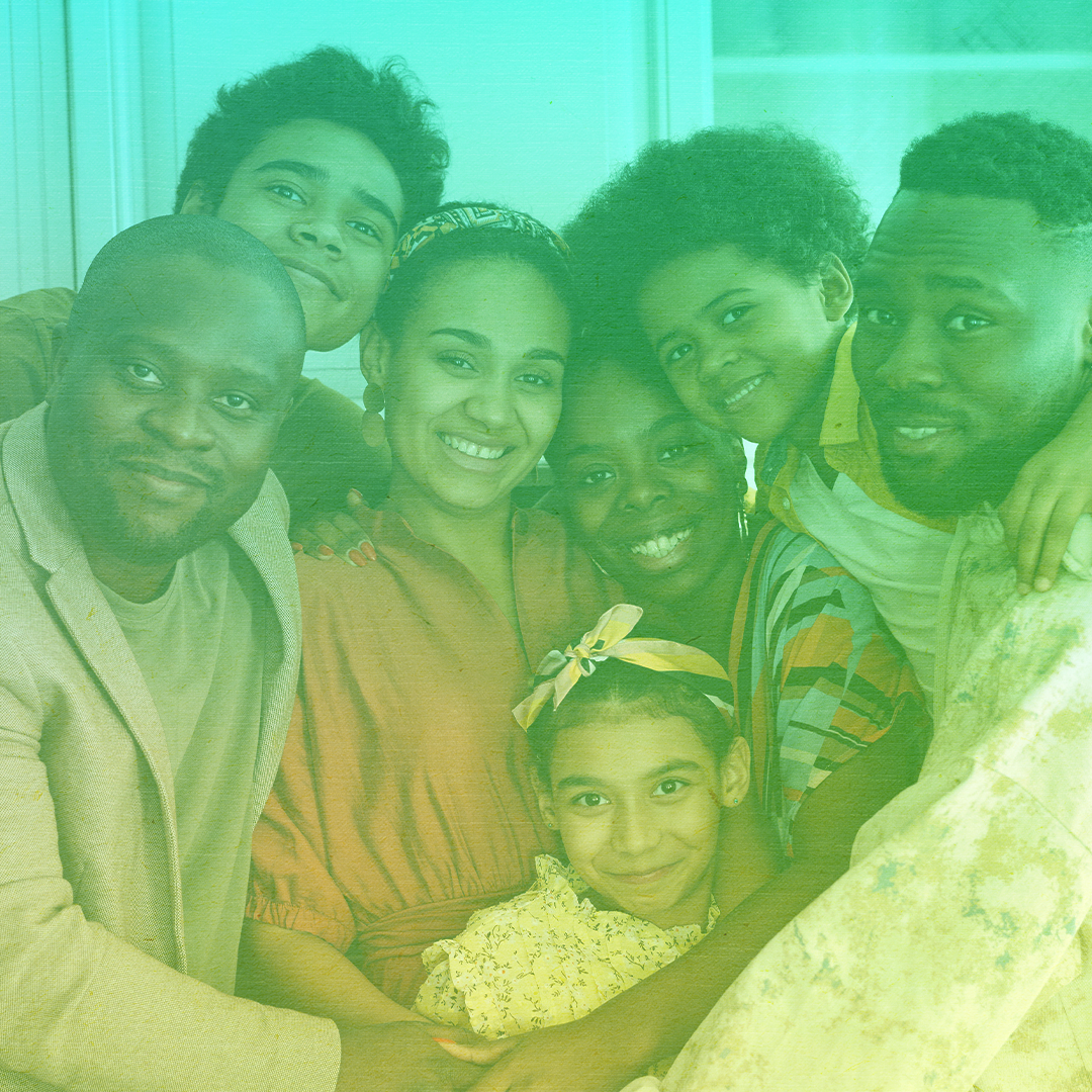 greenish-yellow filtered photo of a Black family with a man and woman and five children all embracing and smiling