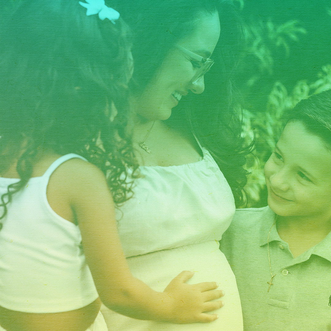 greenish-yellow filtered photo of a pregnant woman embracing a boy and girl child and smiling