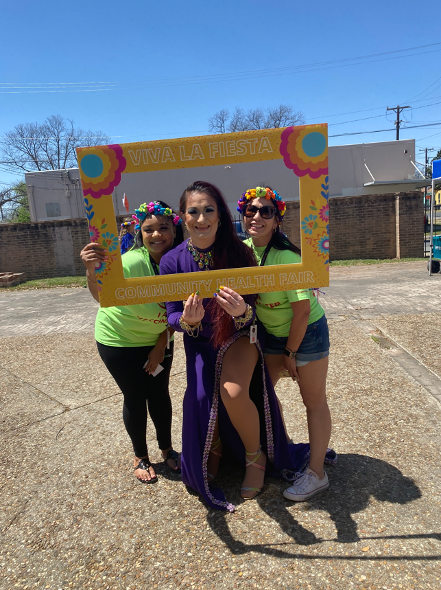 A drag queen and two women post inside a yellow rectangle frame