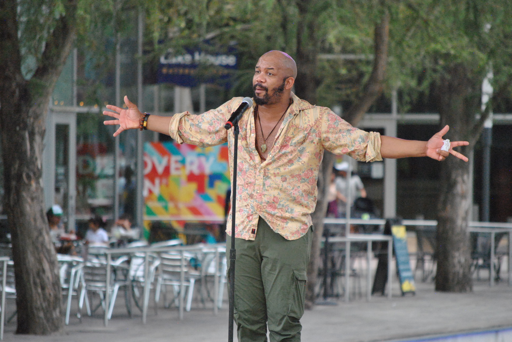Black spoken word poet stands in front of a microphone on an outdoor stage.