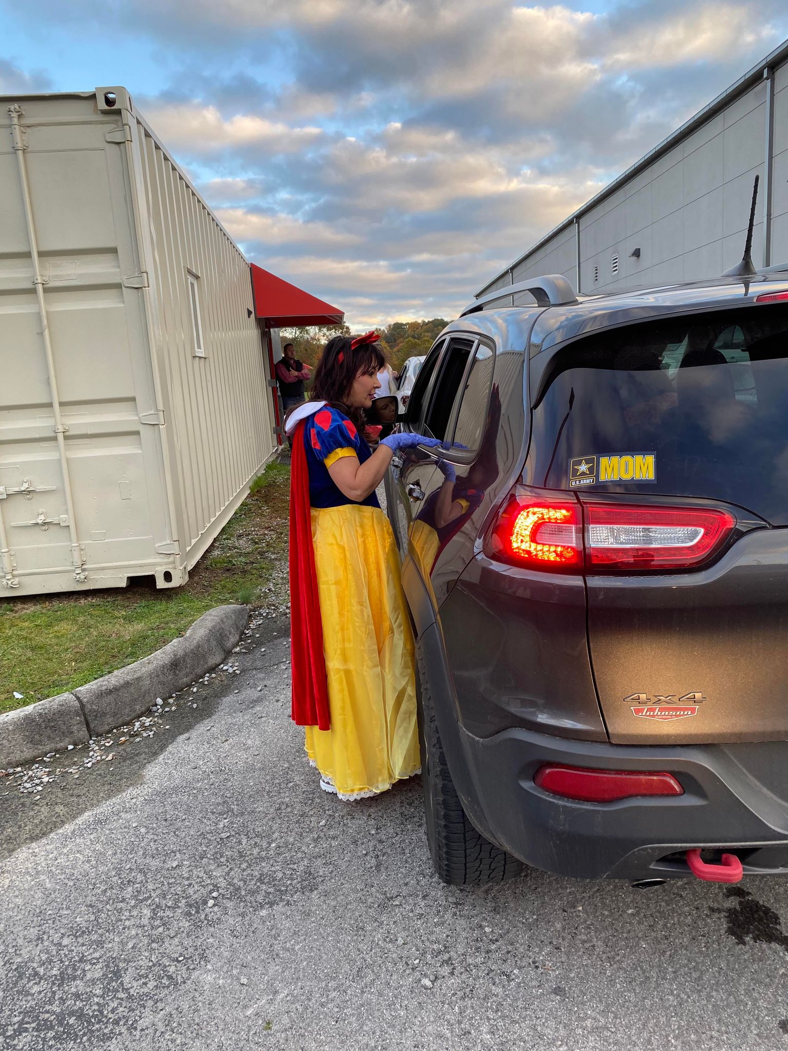 A woman in a Snow White costume talks to a person in a car. 