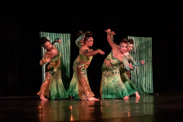 Dancers in green costumes perform on stage