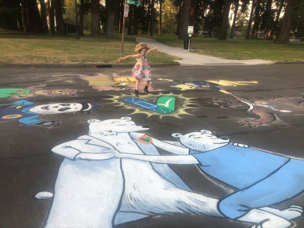 A girl jumps on a chalk drawing of vaccine-related images