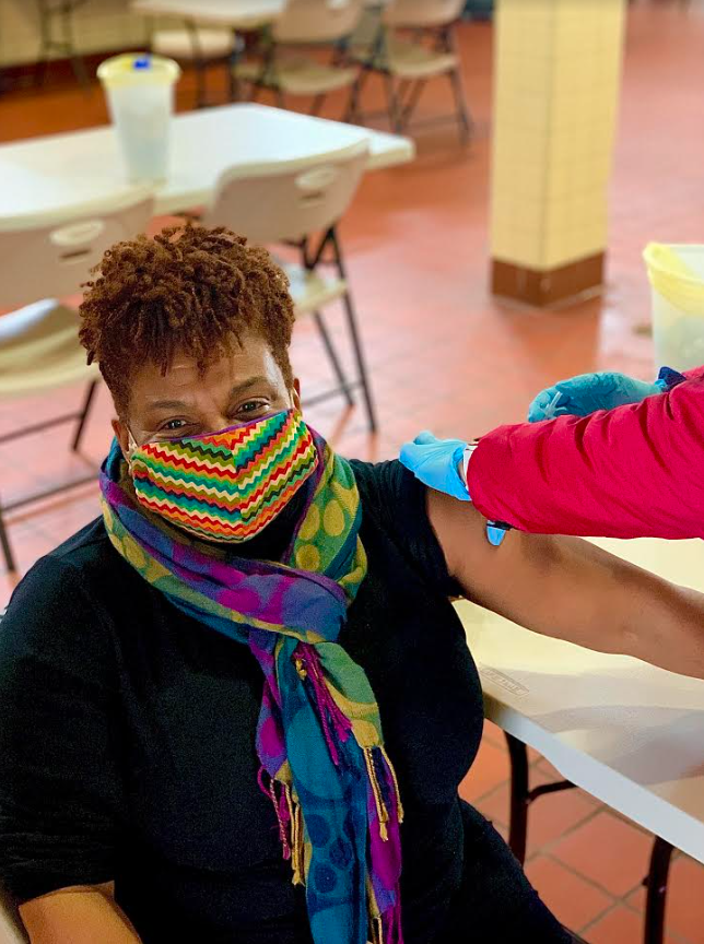 A woman receives a vaccine and is wearing a colorful mask