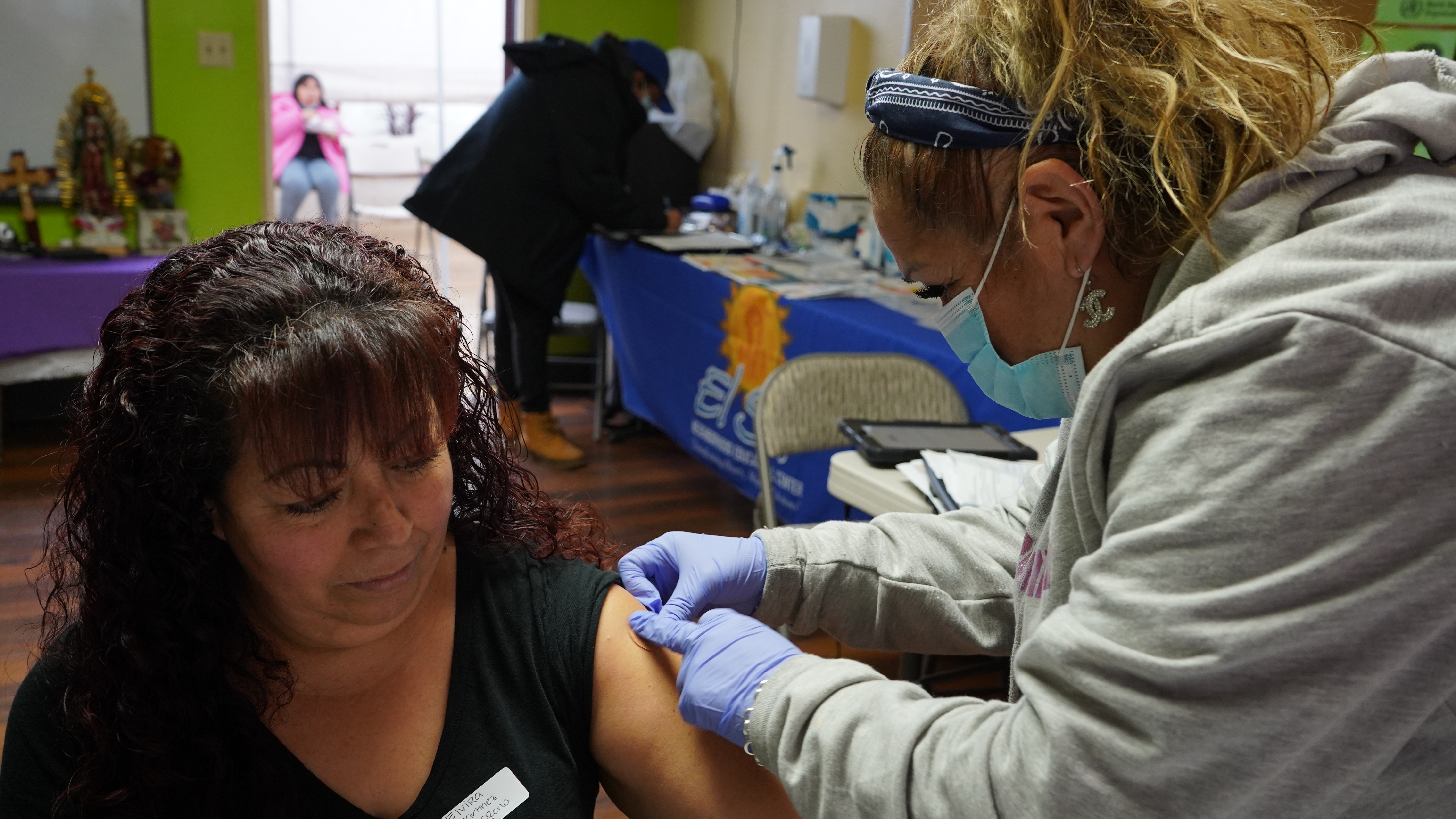 A woman gets an adhesive bandage placed on her arm by a community health worker.