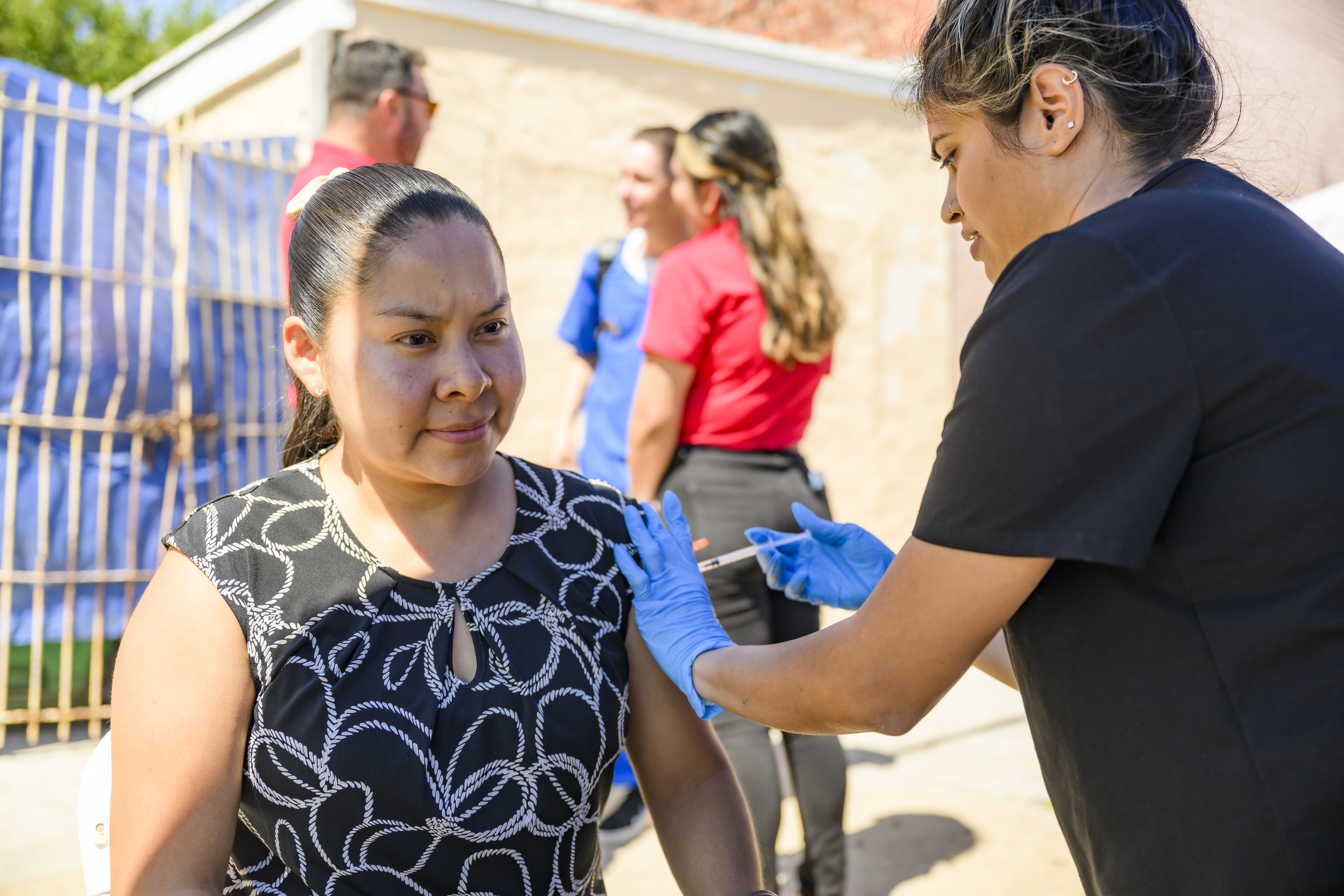 A Hispanic woman sits and gets her vaccination 