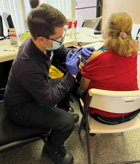 Rosa Hernandez – receiving COVID-19 vaccine, Tyler Gilbert – third year Pharmacy student