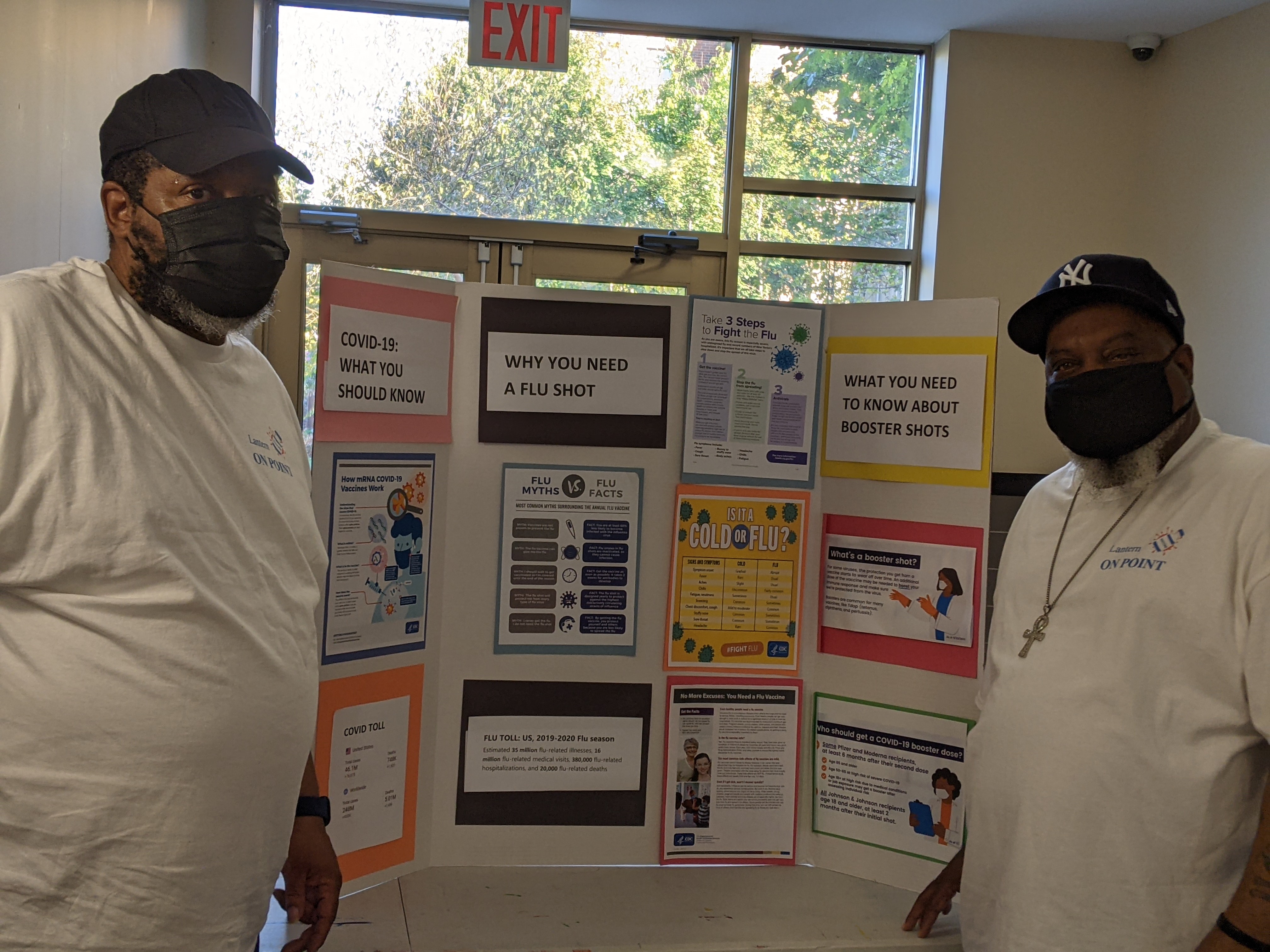 Lantern Community Services staff members stand in front of an informational poster