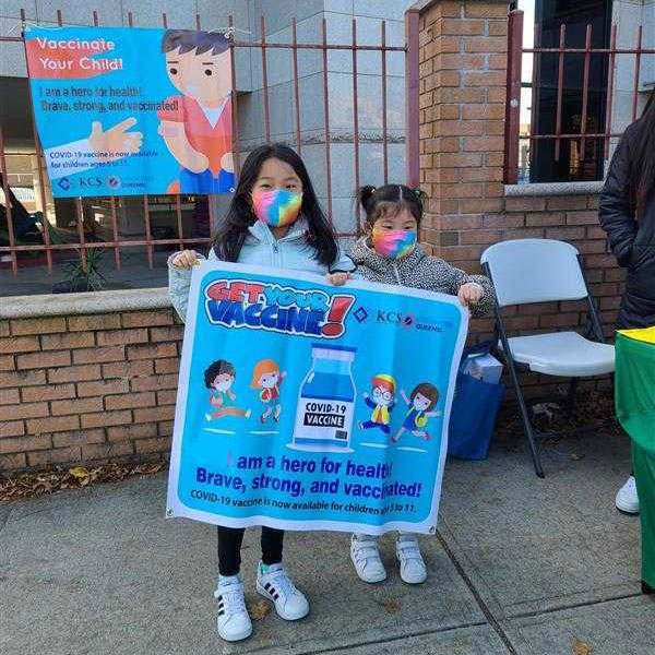 Children holding a 'Get Your Vacccine!' sign