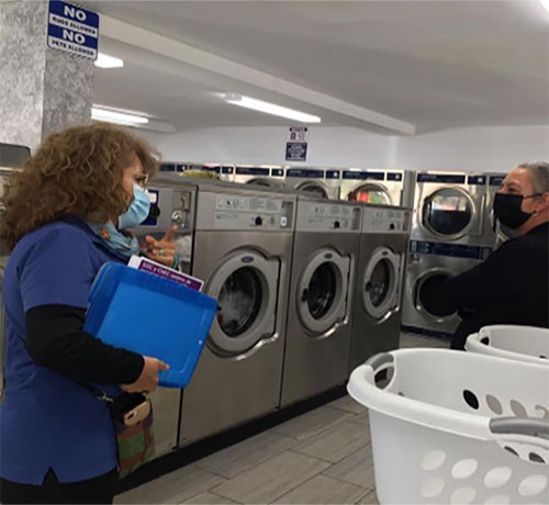 A worker approaches a woman in a laundromat