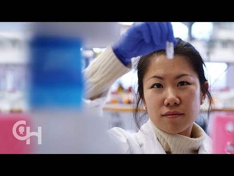 Image of an Asian woman with gloves holding a test tube