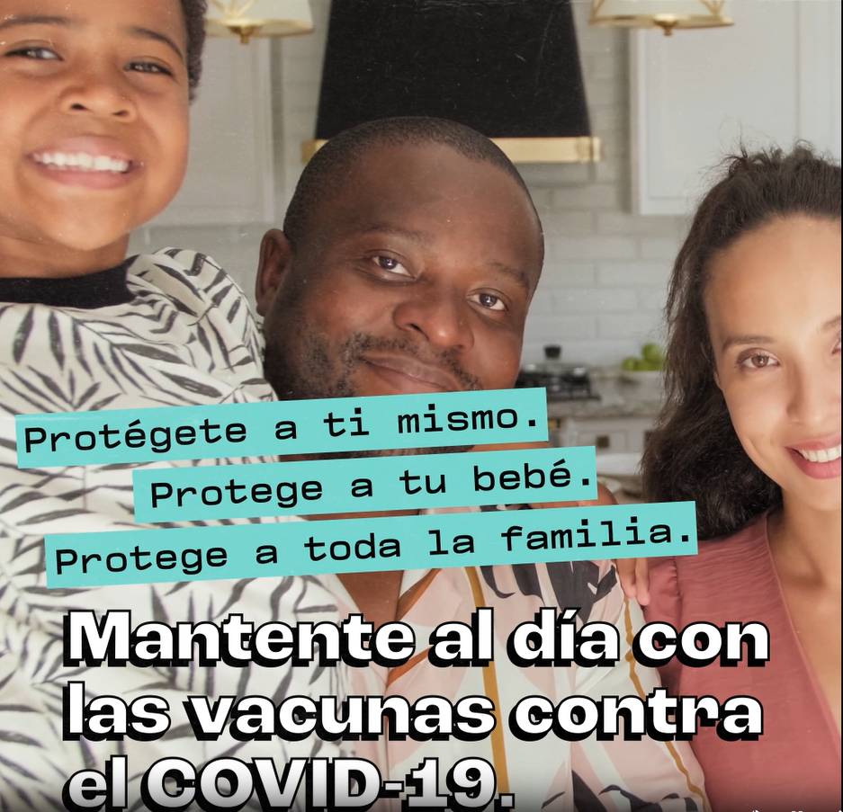 A mixed-race family of three smiles at the camera. Spanish text is shown. The English equivalent is: "Protect yourself. Protect your baby. Protect the whole family. Stay up to date on COVID-19 vaccines."