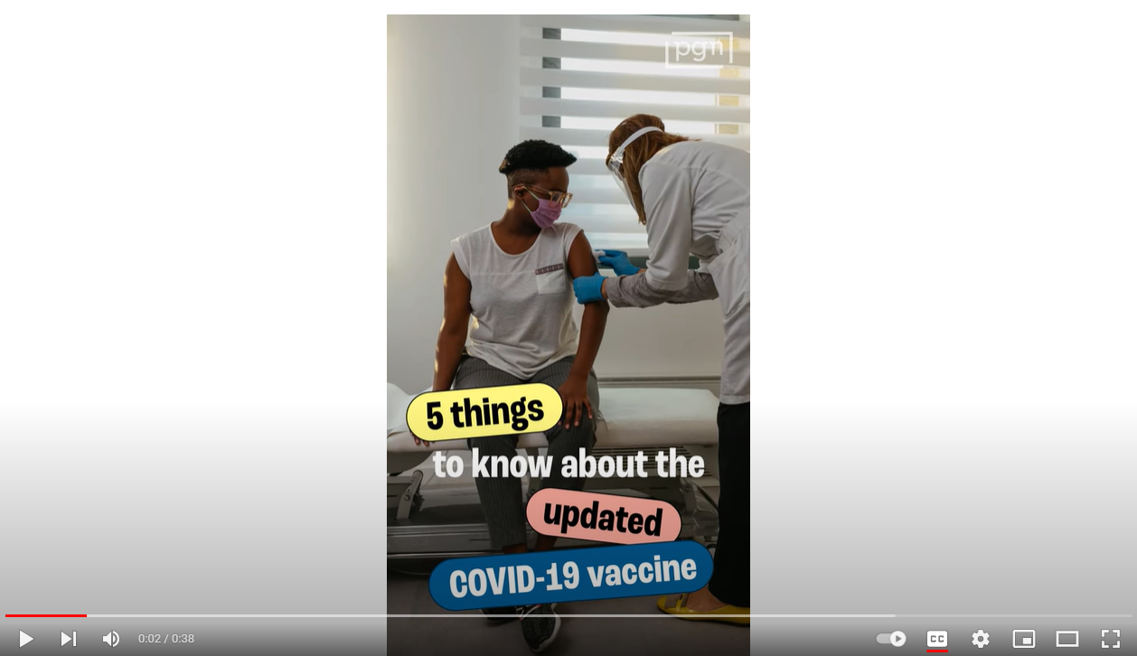 A young Black person sits and receives a vaccination from a health care provider.