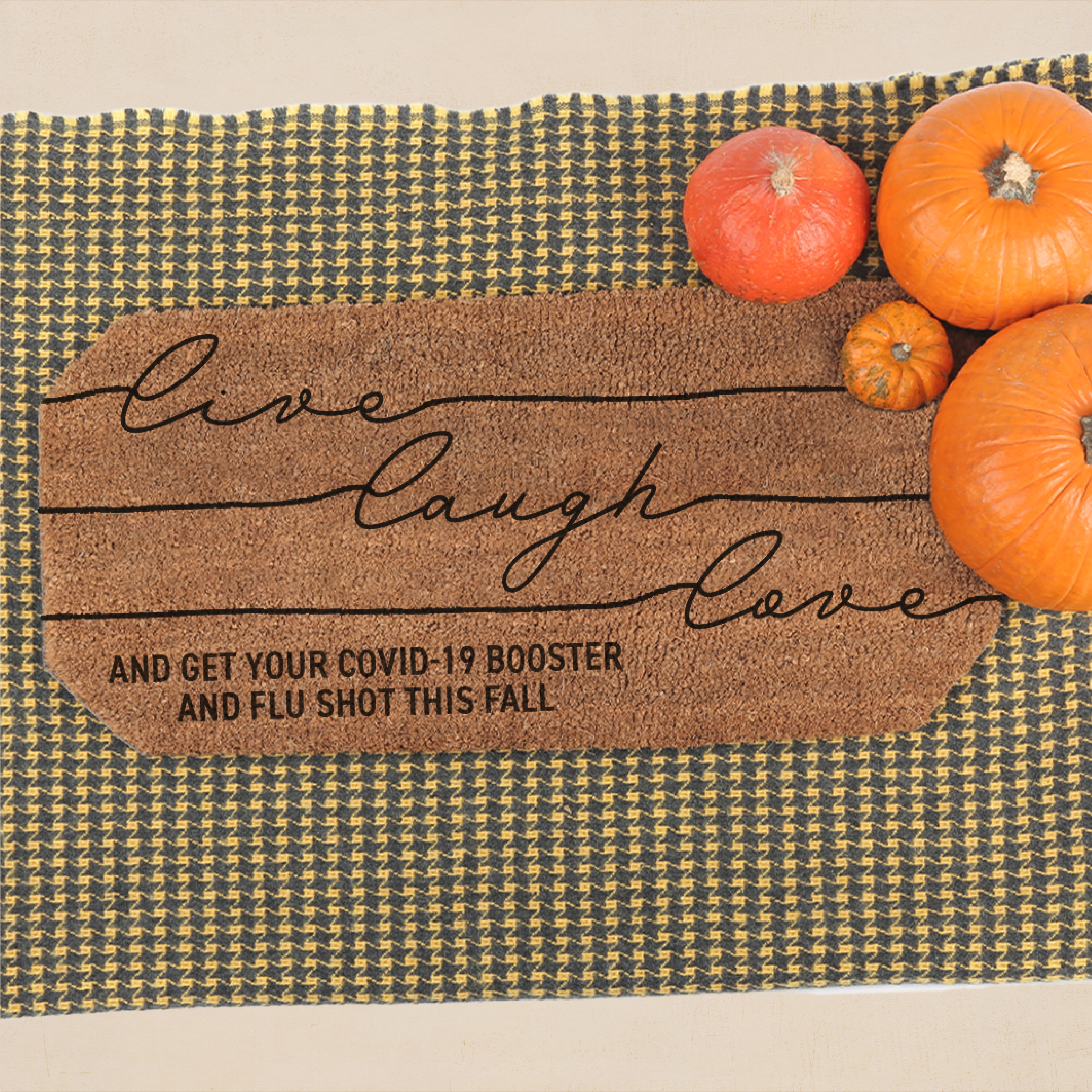 A doormat says "live laugh love and get your COVID-19 booster and flu shot this fall". There is an assortment of pumpkins on the top right corner