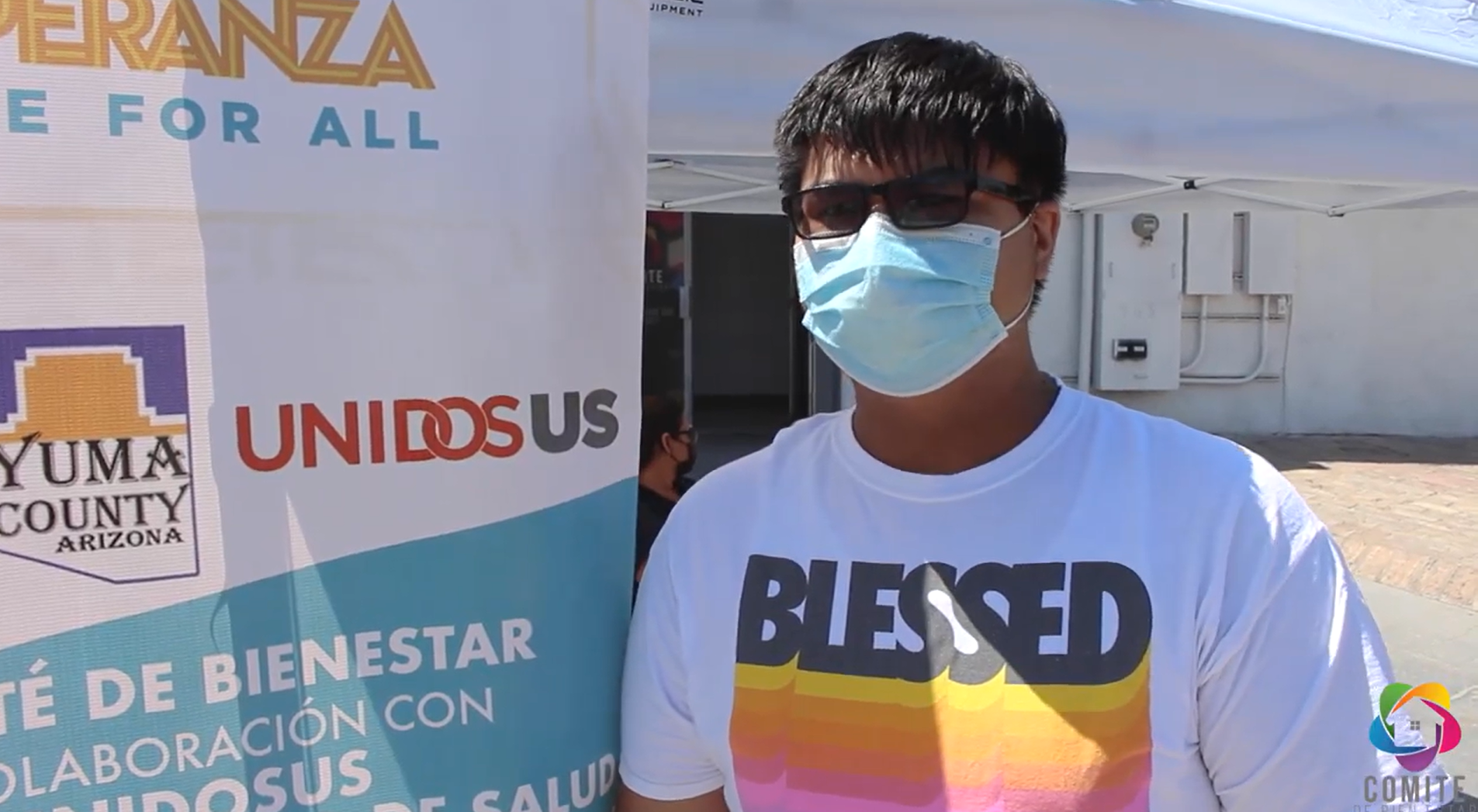 Young adult with mask stands in front of community vaccination site