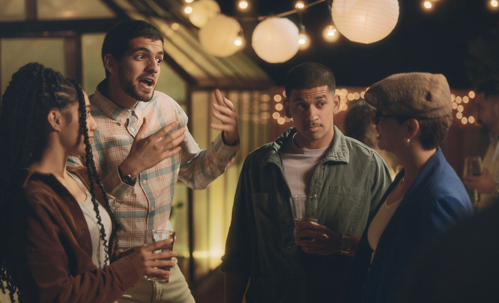 A group of people at a party, with one man speaking enthusiastically.