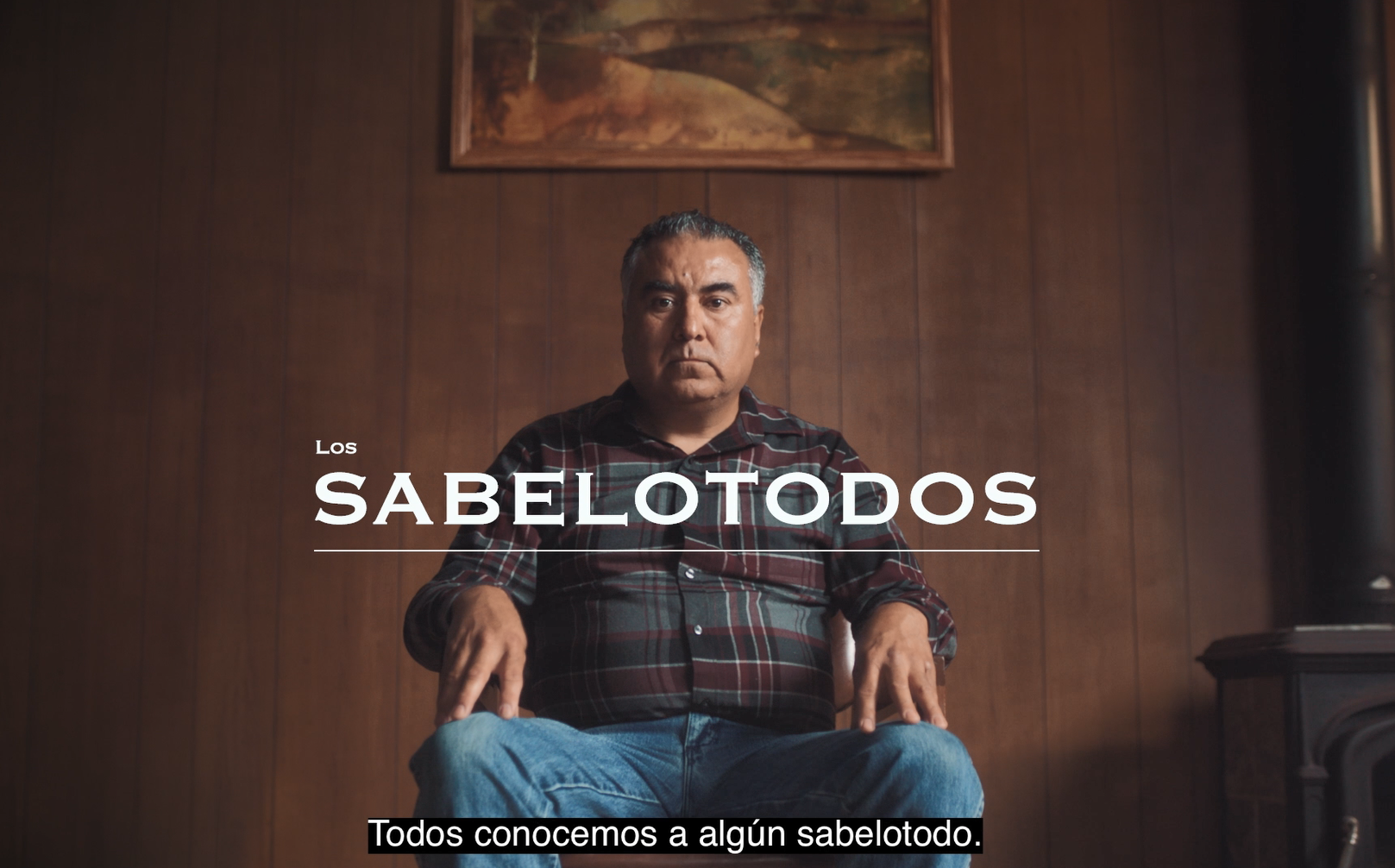 A Hispanic/Latino man sits in a chair in a wood-paneled room. The Spanish title reads, "The Know-It-Alls." Spanish captions read, "We all know someone who's a Know-It-All."