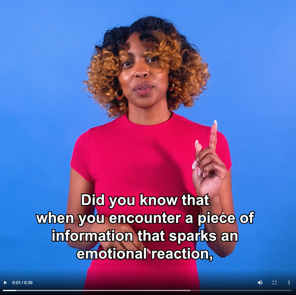 Screenshot from beginning of video. A Black woman wearing a read dress speaks in front of a blue background. Captions read, "Did you know that when you encounter a piece of information that sparks an emotional reaction,"