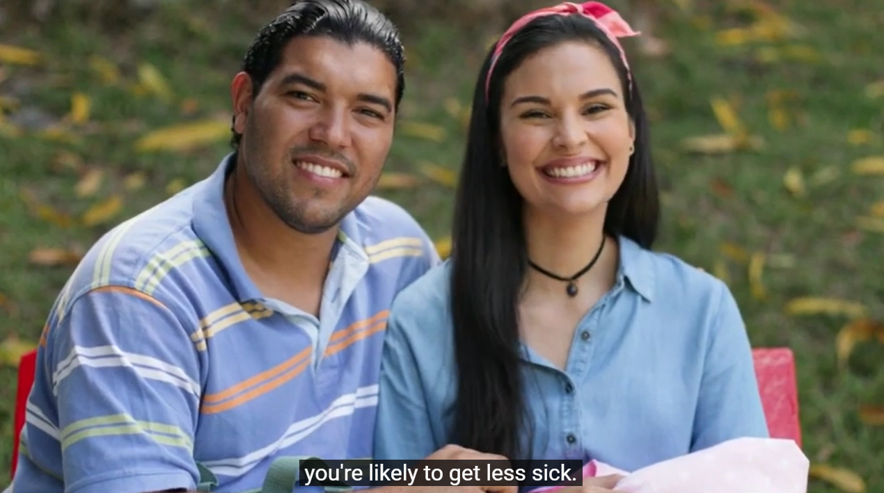 Latinx man and woman holding an infant swaddled in a blanket