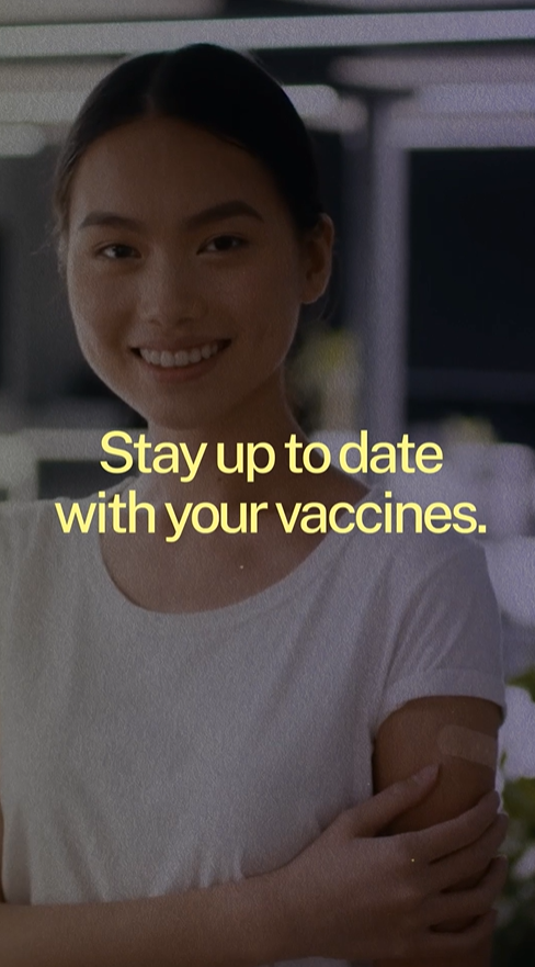 Video still shows a young Asian woman smiling and showing a band aid on her arm.