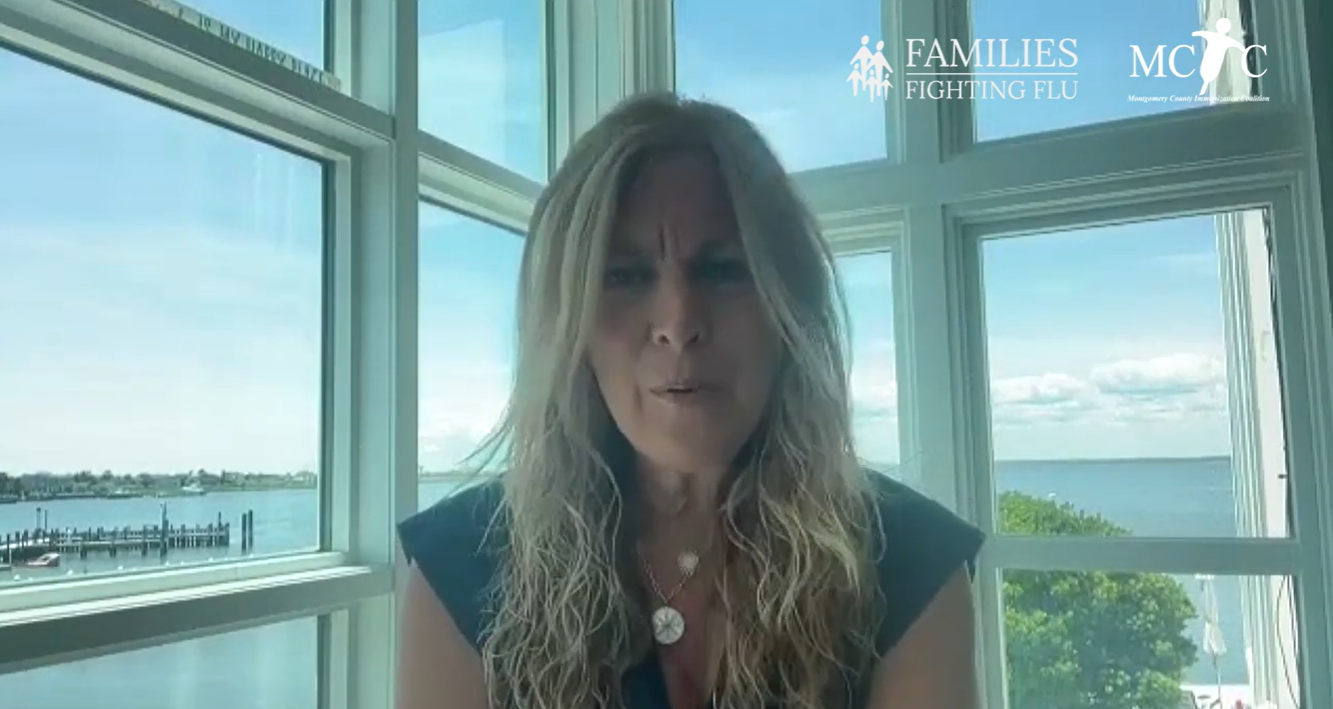 Video still shows a mother talking earnestly to the camera sitting in front of a large set of windows.