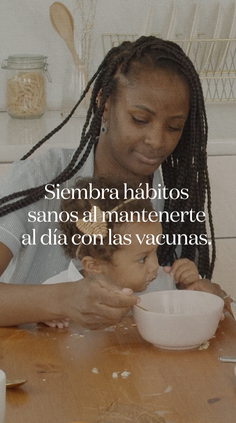 Video still shows a Black mother feeding her daughter oatmeal at the kitchen table.