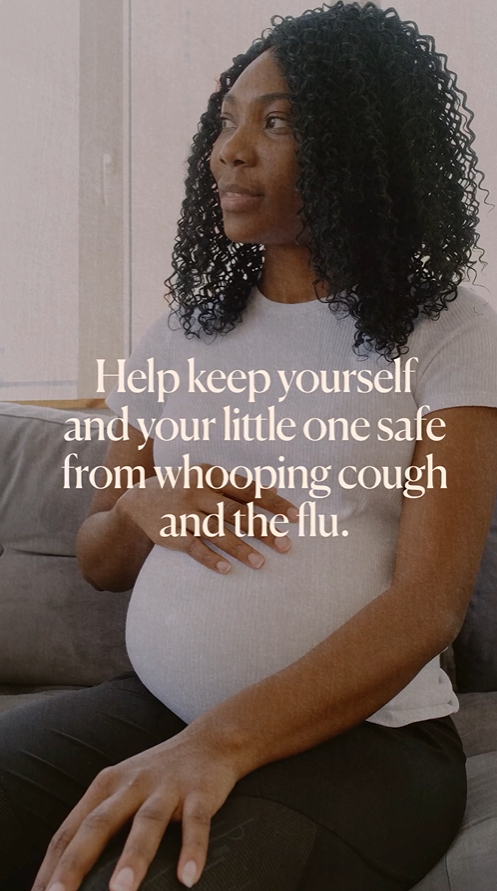 Video still shows a Black woman sitting on a couch, smiling and caressing her pregnant belly.