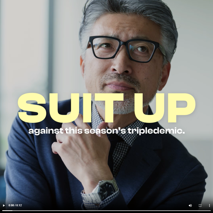 An Asian man wearing a suit and glasses poses 
