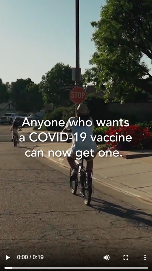 A child and an adult ride their bikes on the street with text overlaid noting that anyone can get a vaccine who wants one (specific eligibility criteria shared later in video)