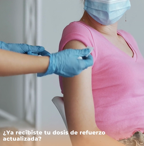 Woman in pink shirt getting a COVID-19 booster.