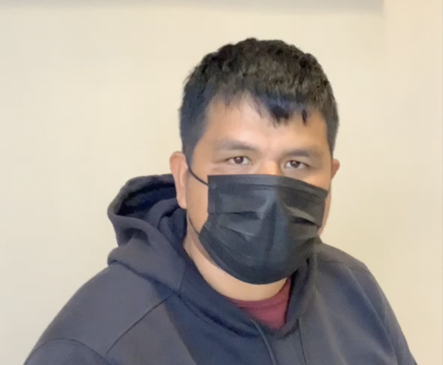 A person wearing a mask poses and faces the camera