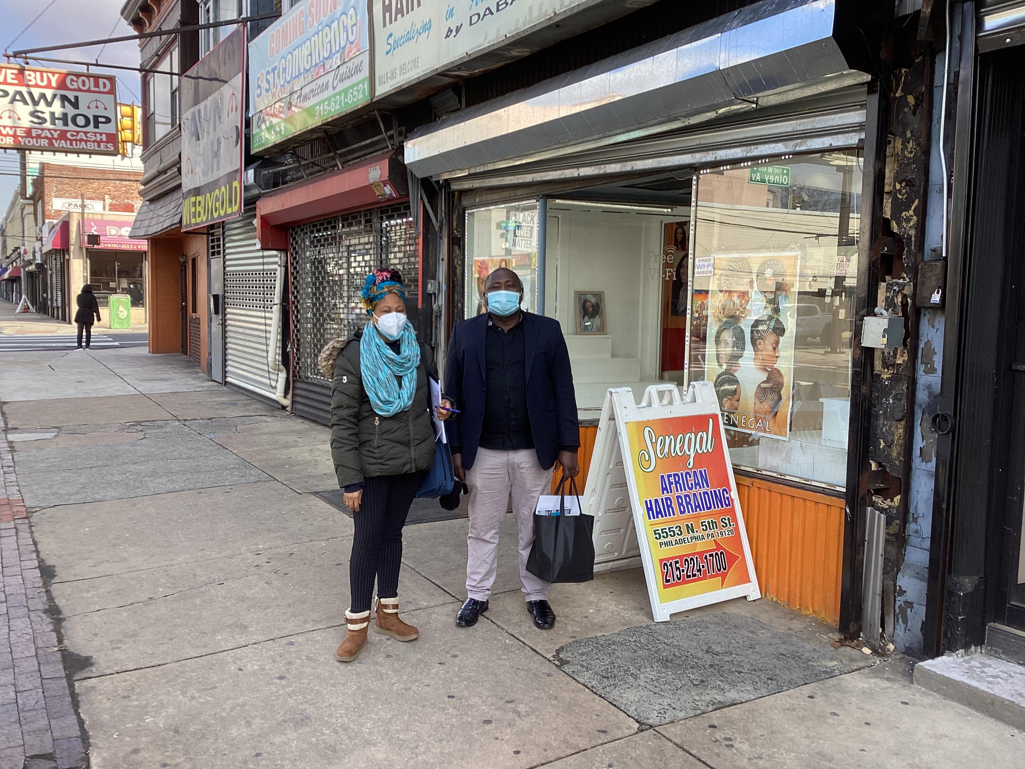 Two adults stand outside a Philadelphia storefront